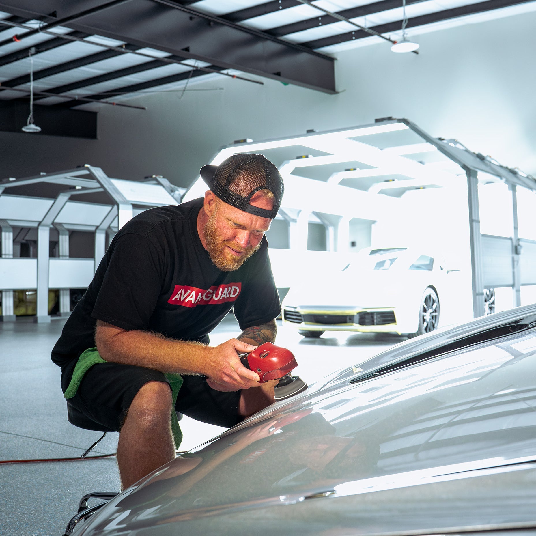Eron Knox sitting in front of a McLaren working on polishing the paint.